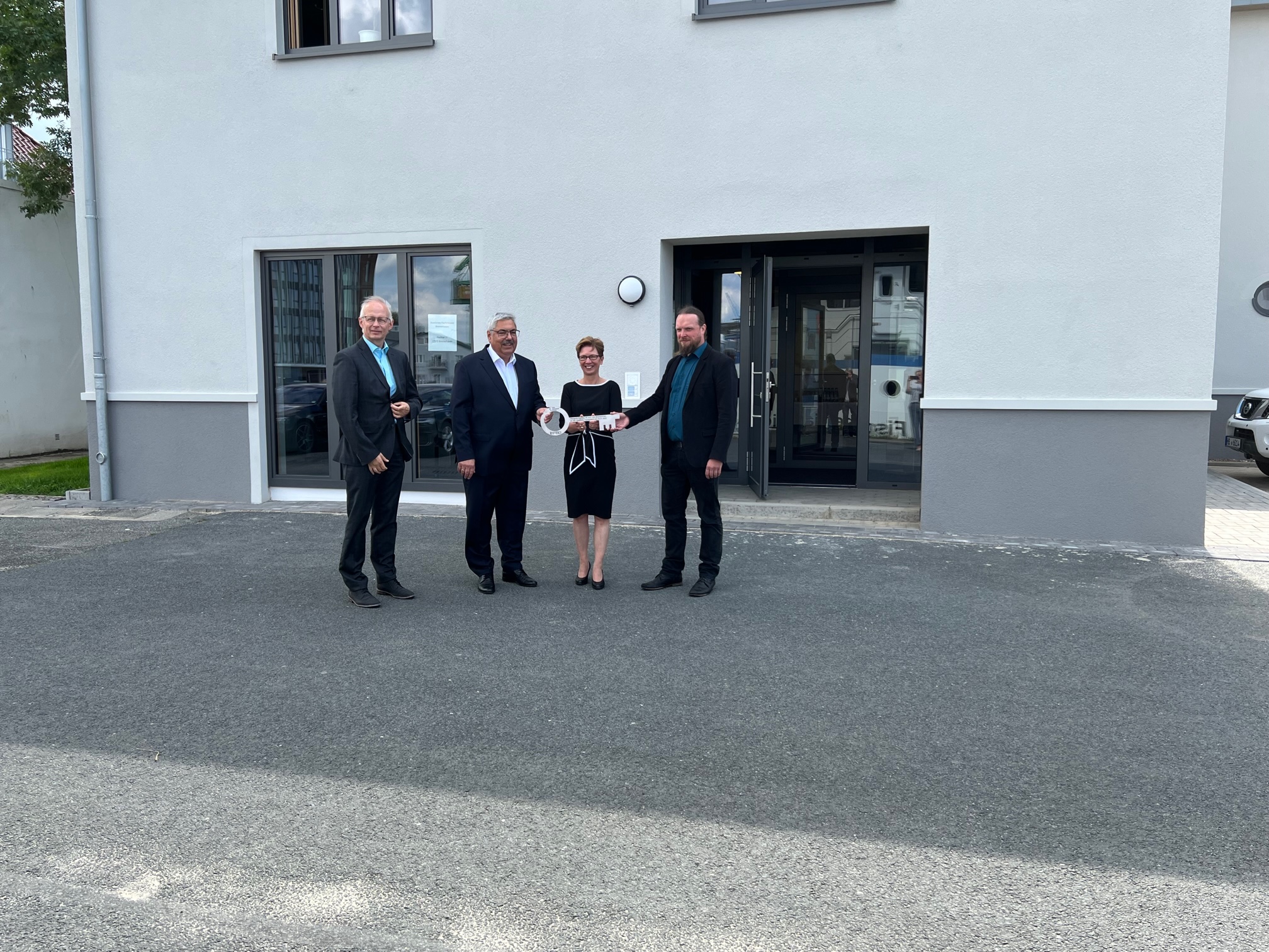 Gruppenfoto einer Schlüsselübergabe vor dem neu sanierten Bürogebäude am Fischkai für das Fischereiamt im Fischereihafen.