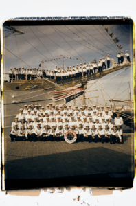 Gruppenfoto einer Schiffsbesatzung vor einem Segelschiff